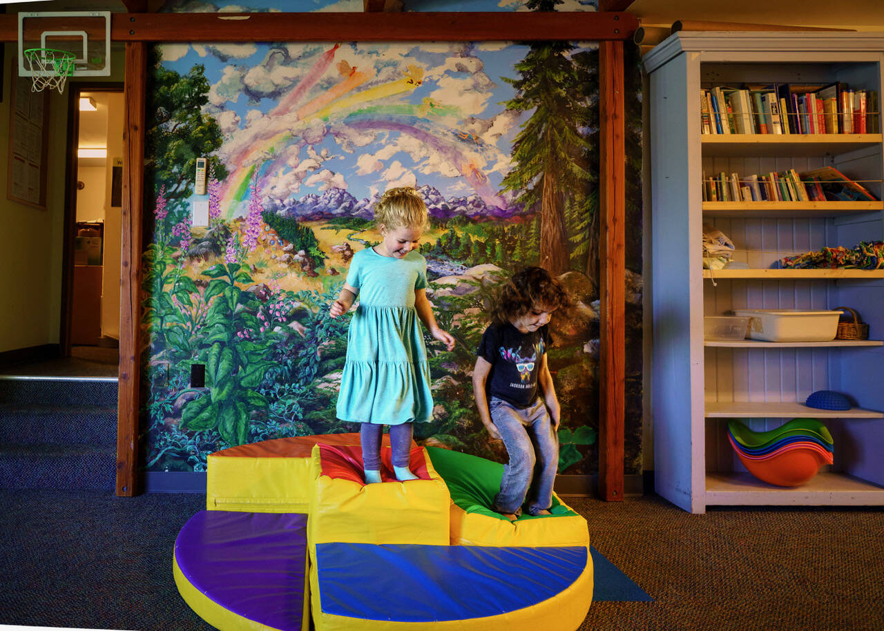 Callie Edwards, 4, and Rory Dafick, 4, jump up and down in front of a rainbow mural. (Photo by David Welton)