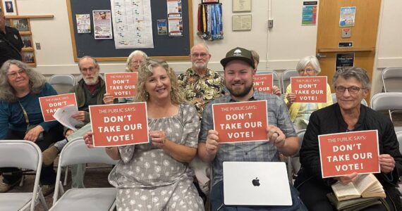 Members of the Whidbey Environmental Action Network, Garry Oak Society and Whidbey community hold "Don't take our vote!" signs at the Aug. 13 Oak Harbor city council meeting. (Photo by Amanda Bullis)