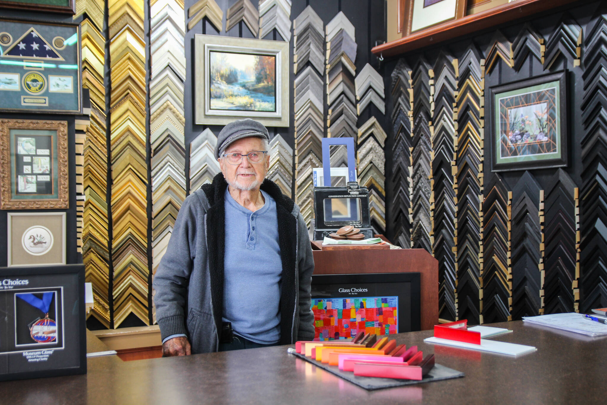 Gene Phelps stands behind the counter at Gene’s Art & Frame, the business he opened in 1967. (Photo by Luisa Loi)